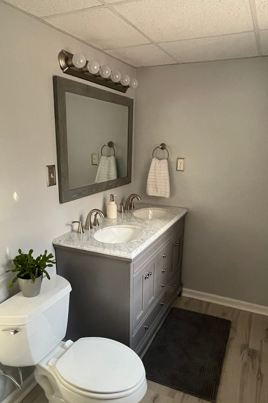 A bathroom with a toilet , sink and mirror.