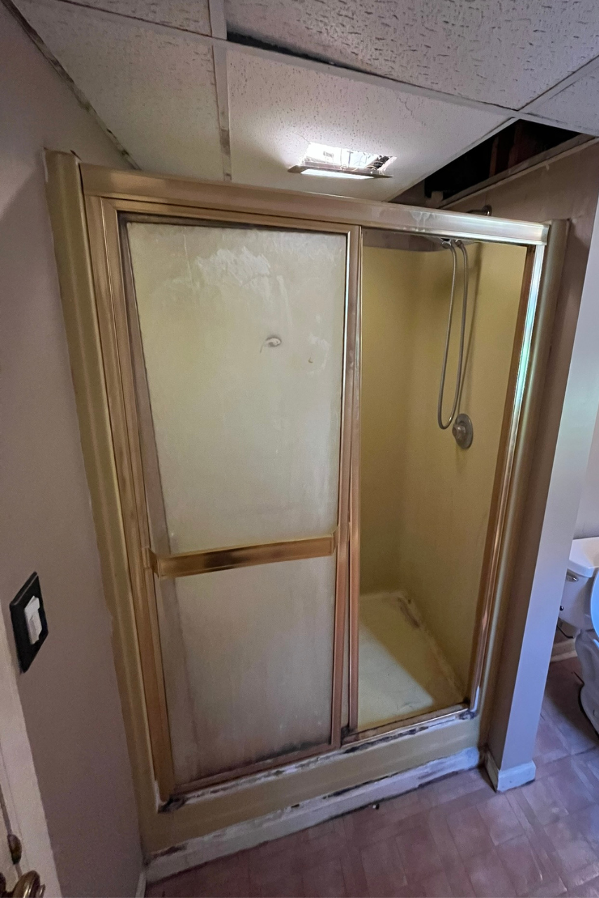 A bathroom with a sliding glass shower door and a toilet.