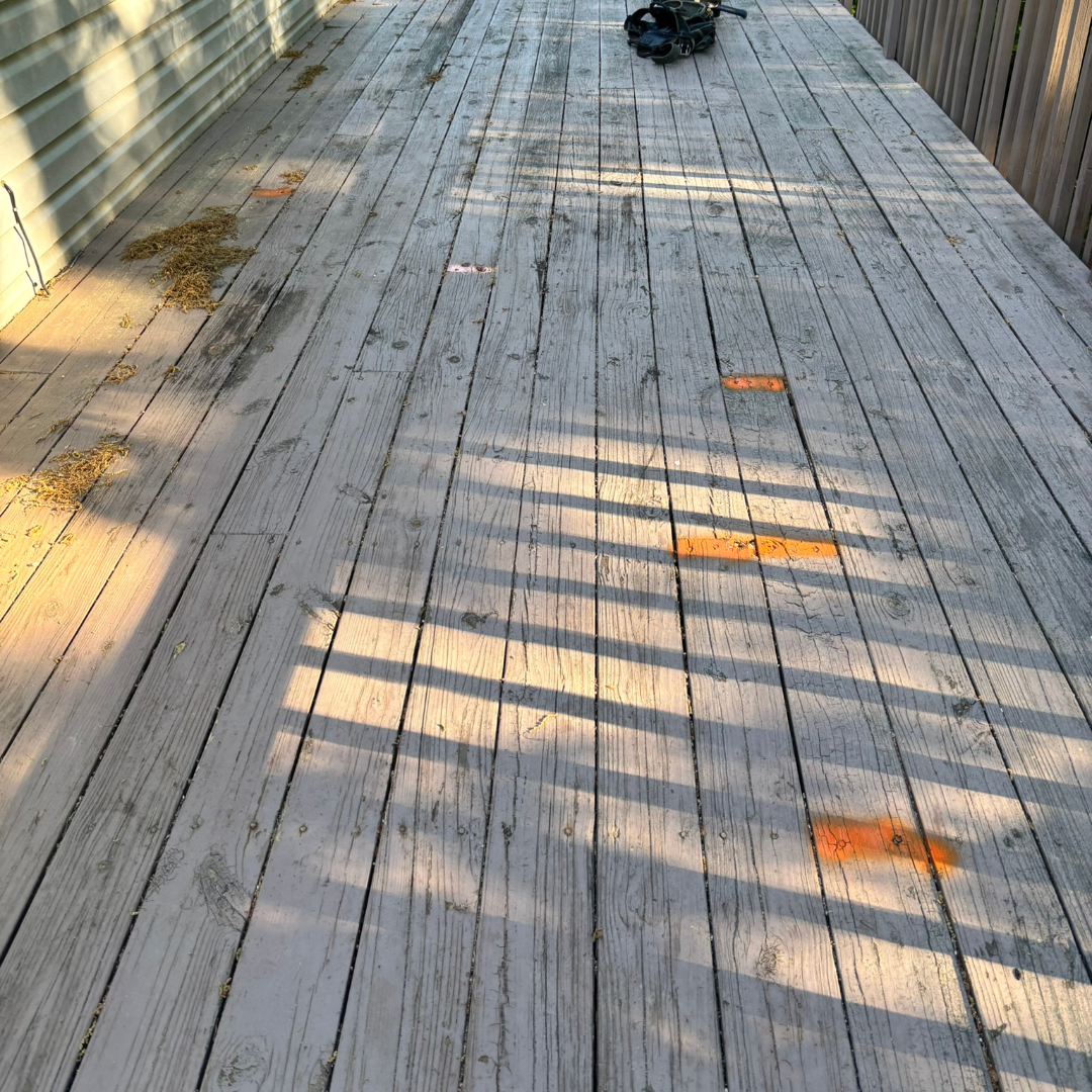 A wooden deck with benches and leaves on it.