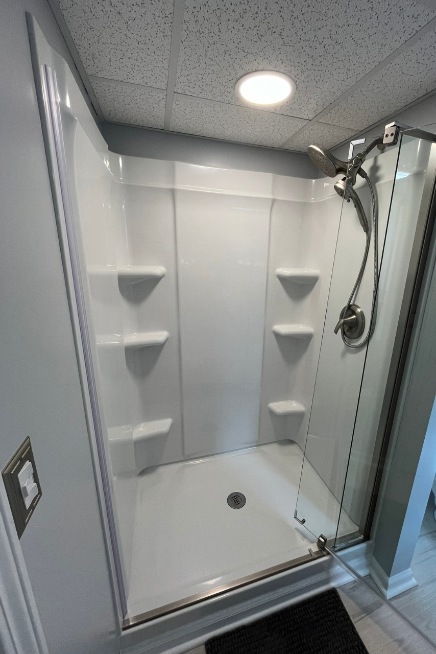 A shower stall with a glass door and shelves in a bathroom.