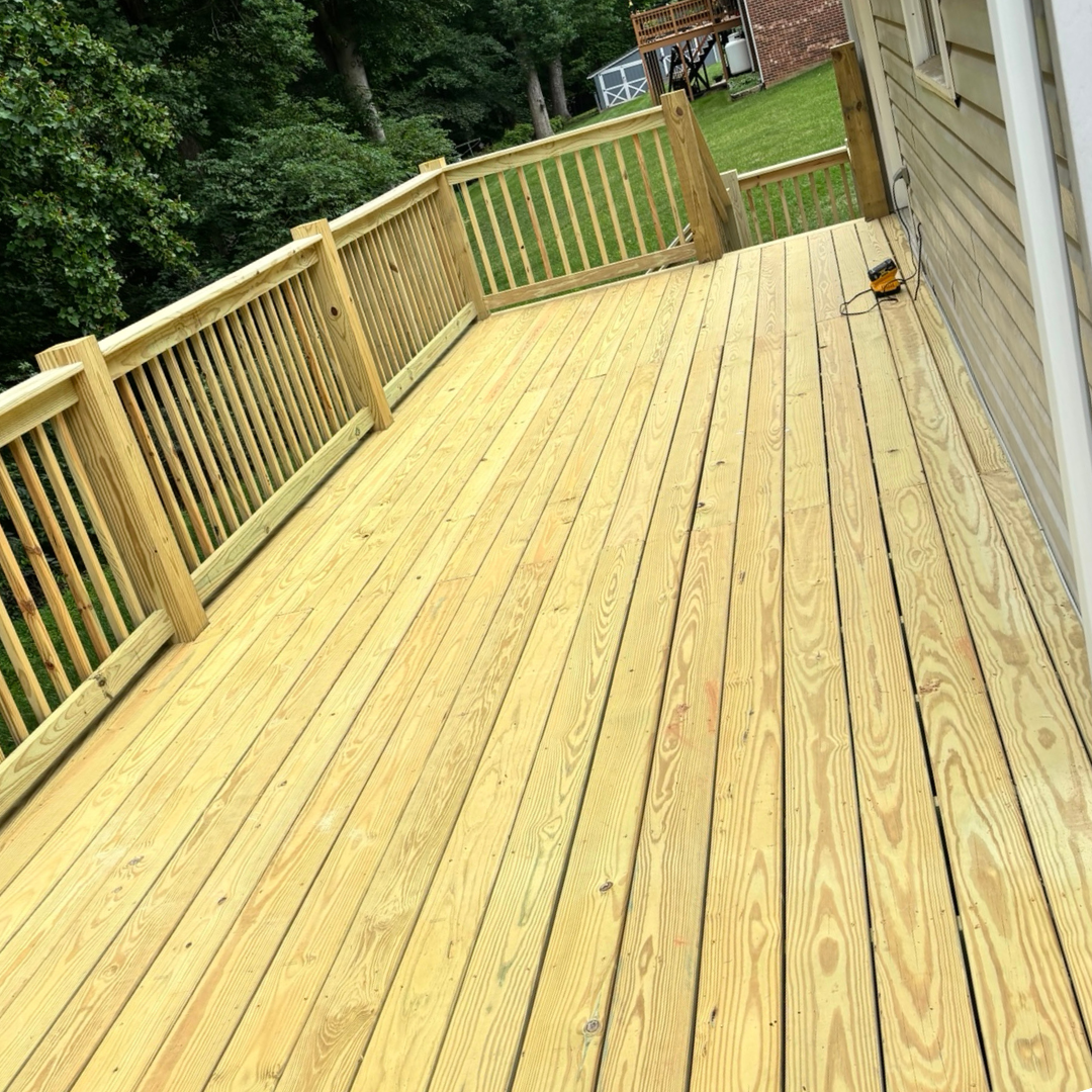 A wooden deck with a railing and trees in the background.