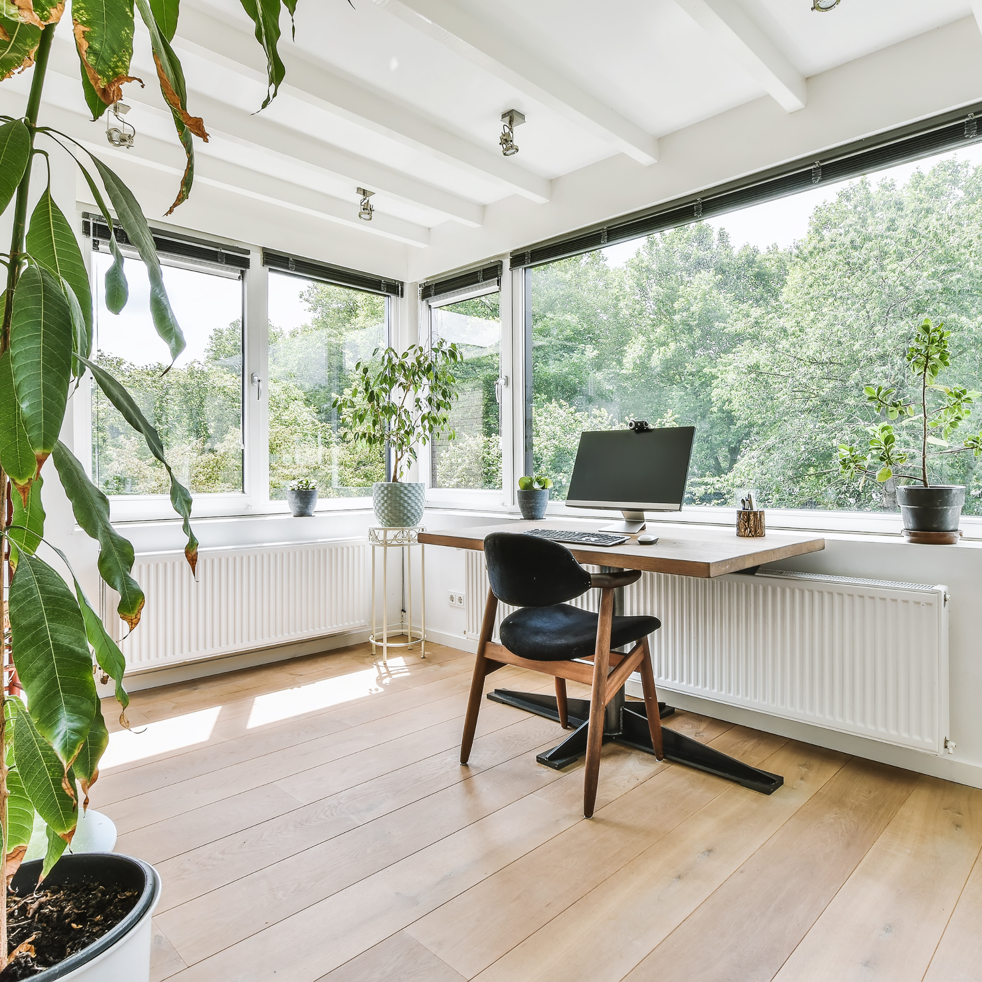 A desk with a computer on it in a room with lots of windows.