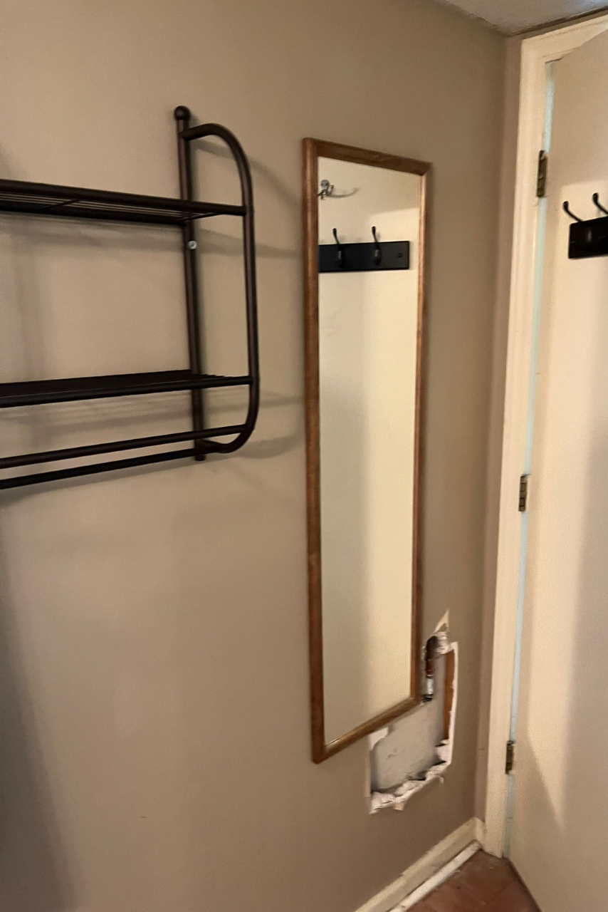 A hallway with a mirror and a shelf on the wall