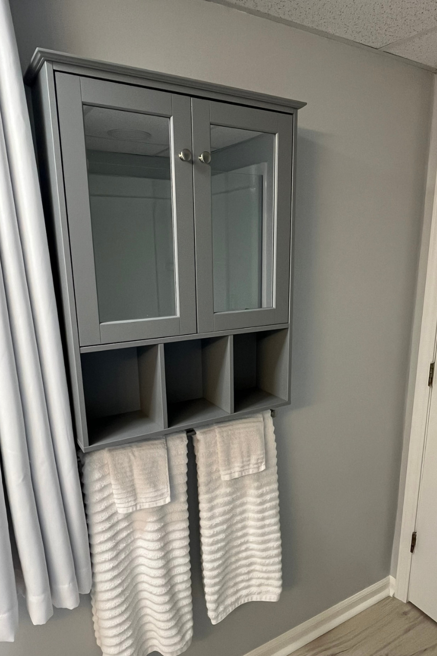 A bathroom cabinet with a mirror and towels hanging from it.