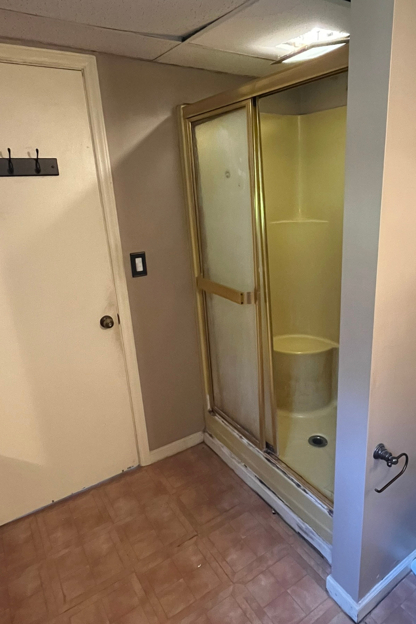 A bathroom with a shower stall and a door.