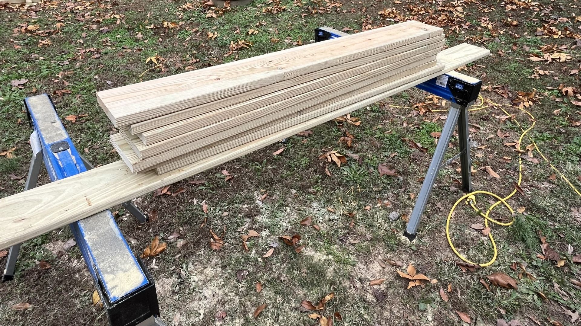 A stack of wood sitting on top of a saw horse.