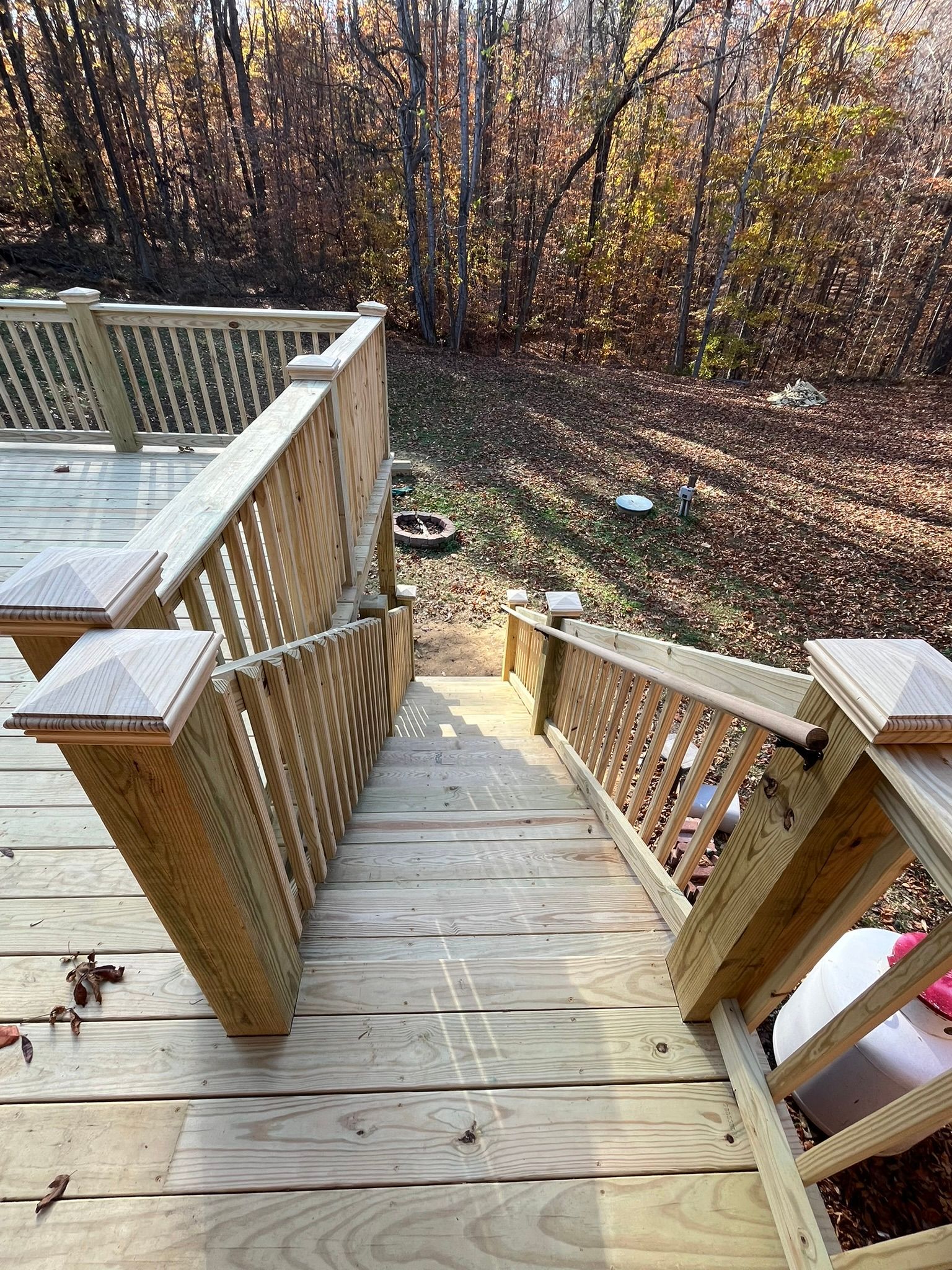 A wooden deck with stairs leading up to the woods.
