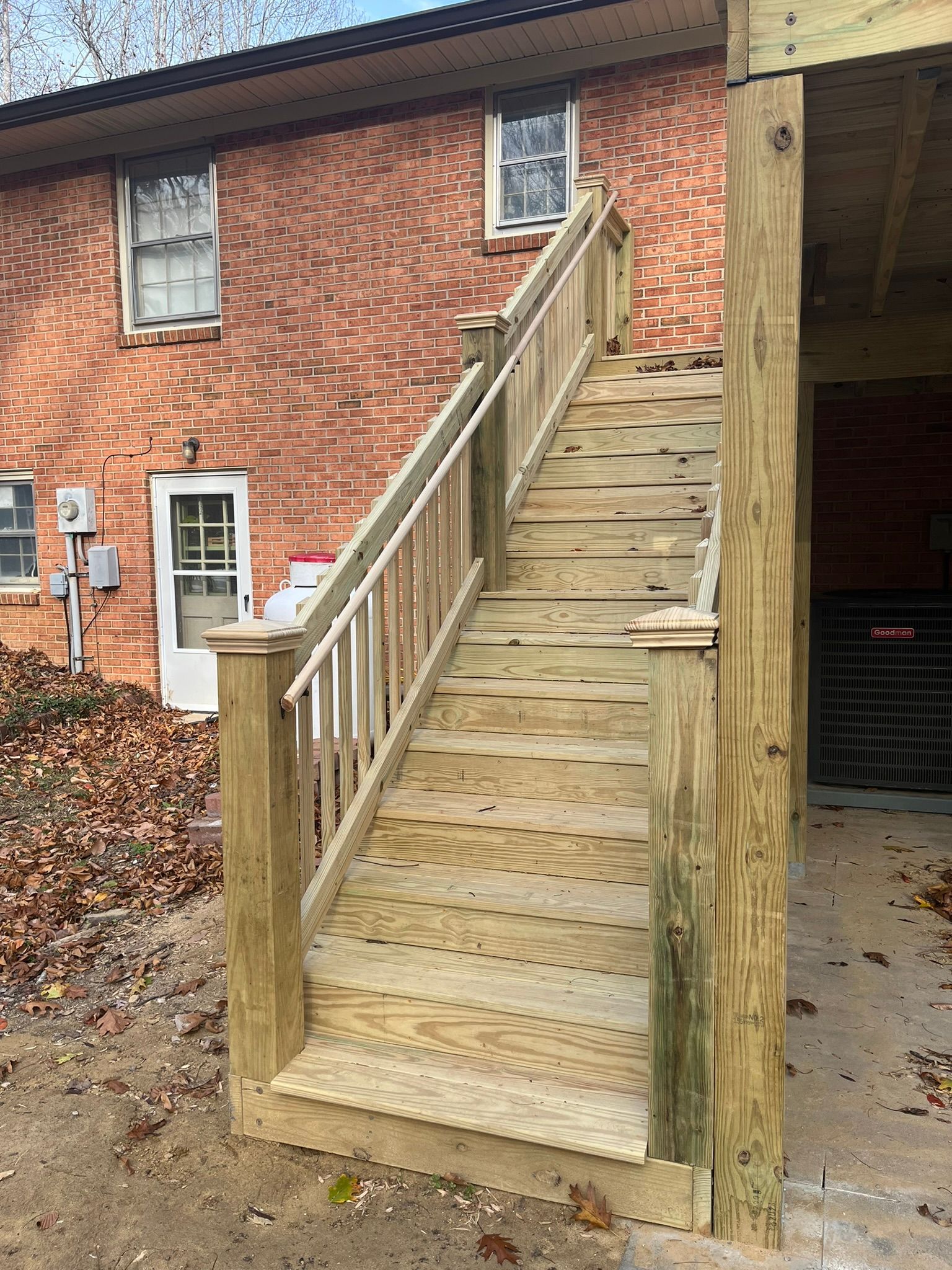 A wooden deck with stairs leading up to a brick house.