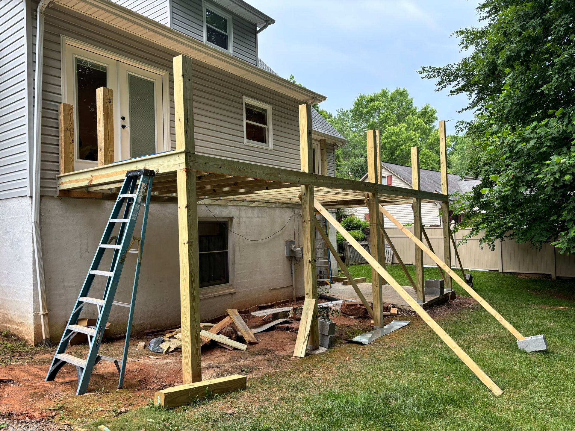 A wooden deck is being built in the backyard of a house.