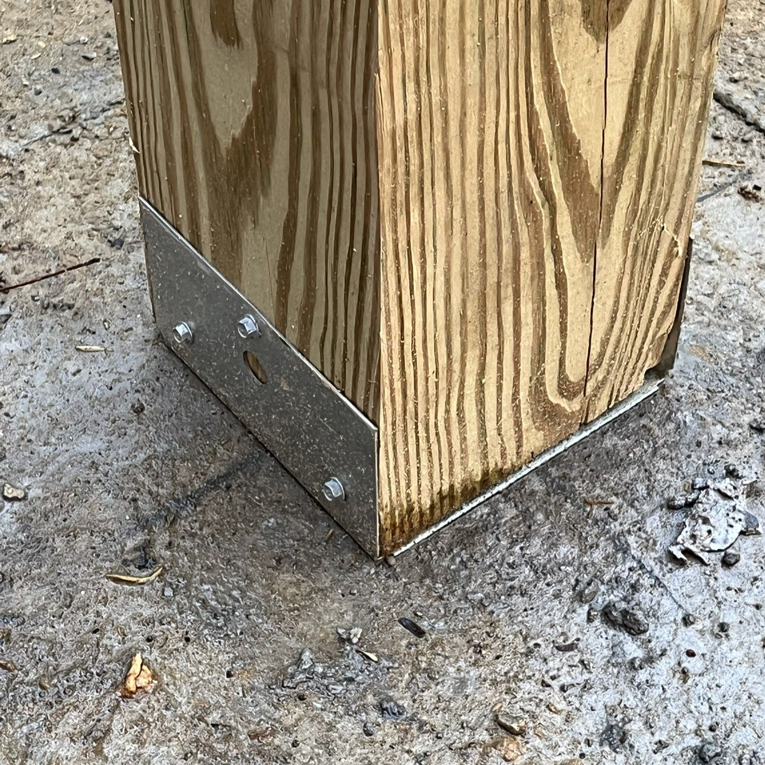 A close up of a wooden post with a metal bracket attached to it.
