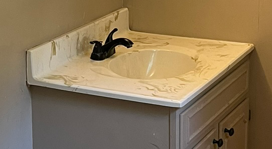 A bathroom sink with a marble counter top and a black faucet.