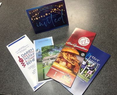 A bunch of brochures are sitting on a table with an invitation card