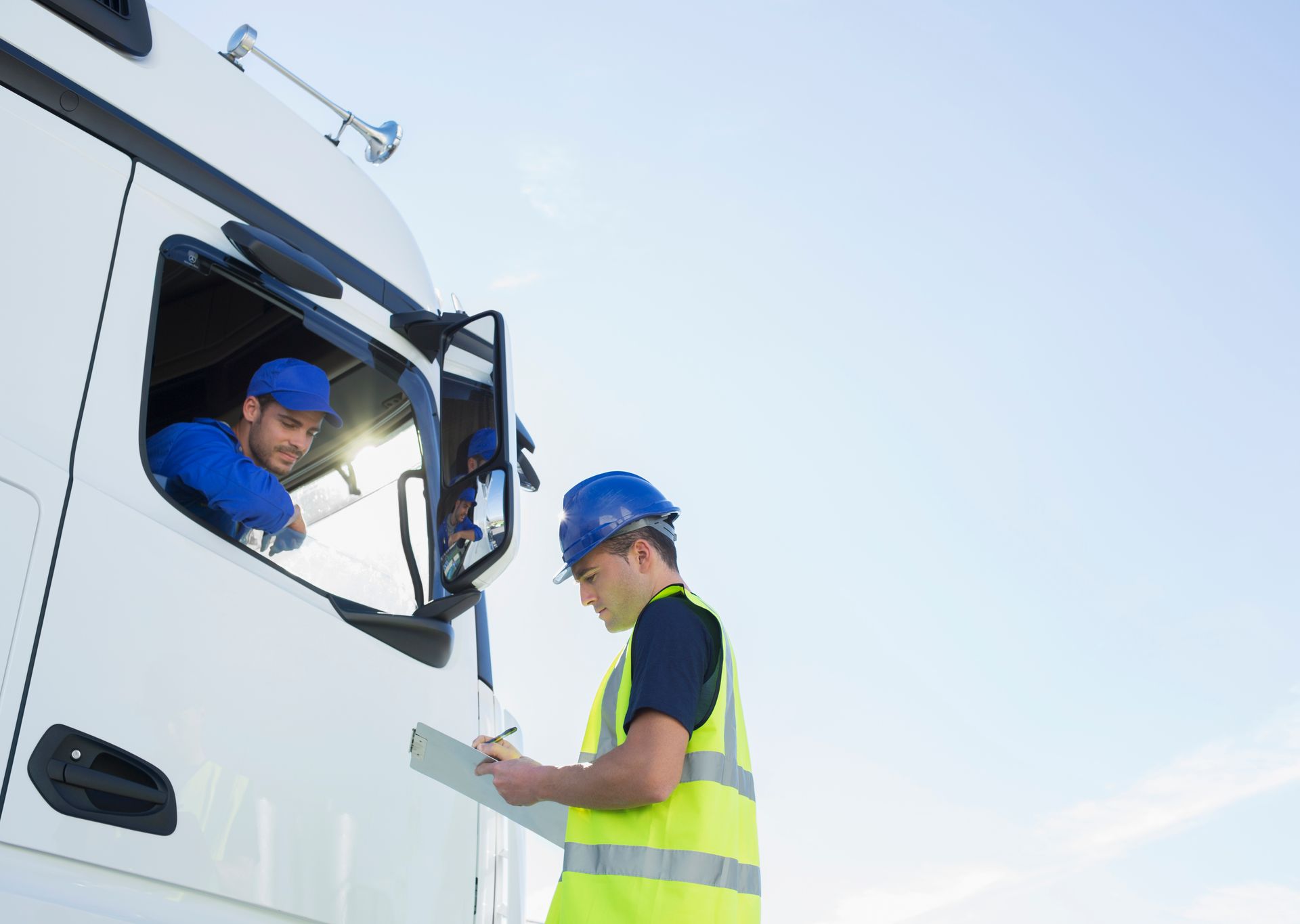 Un uomo sta scrivendo su un blocco per appunti davanti a un camion.