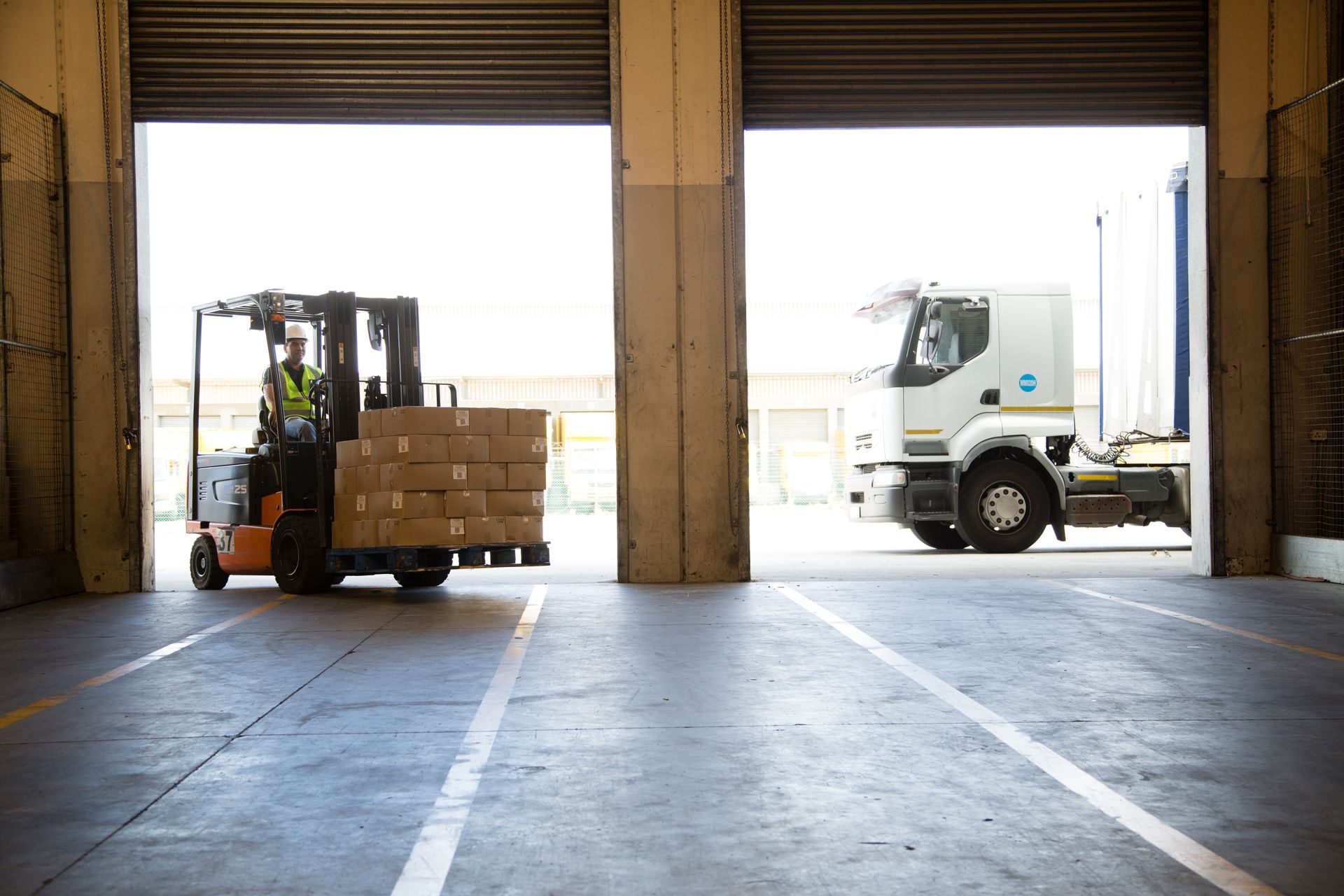 Un carrello elevatore carica delle scatole su un camion in un magazzino.