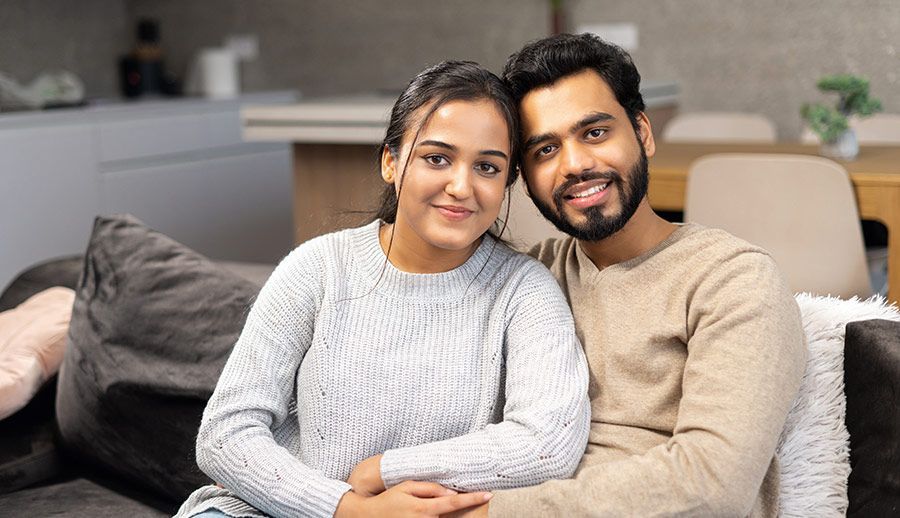 Two smiling people sitting together on a couch in a cozy living room