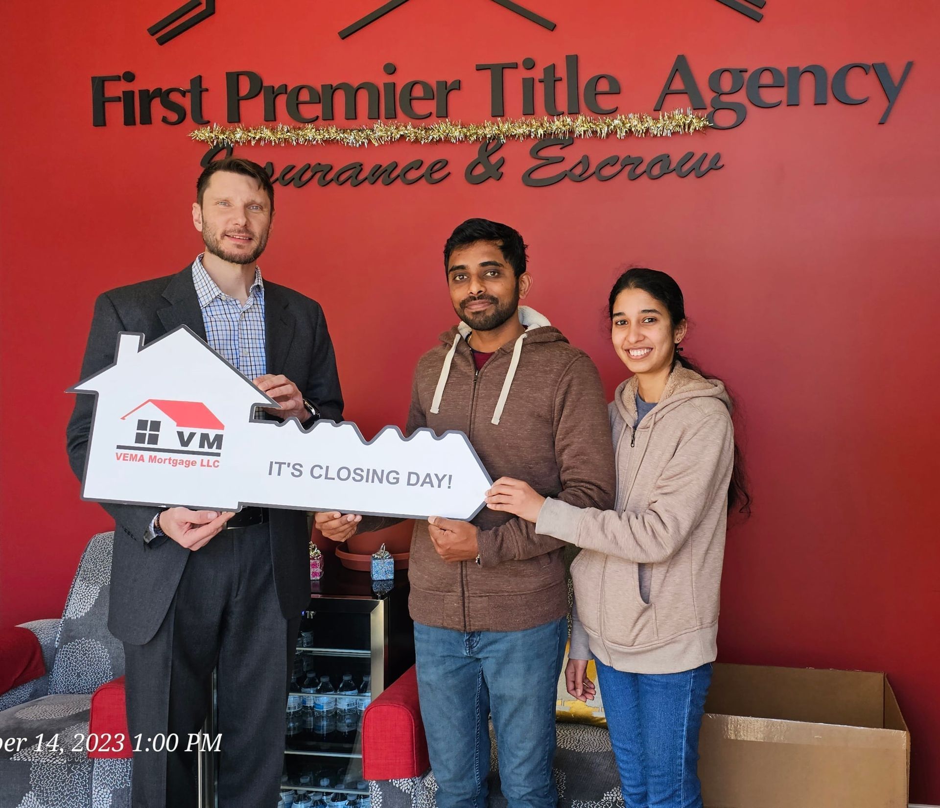 Three people holding a giant check in front of a red First Premier Title Agency wall