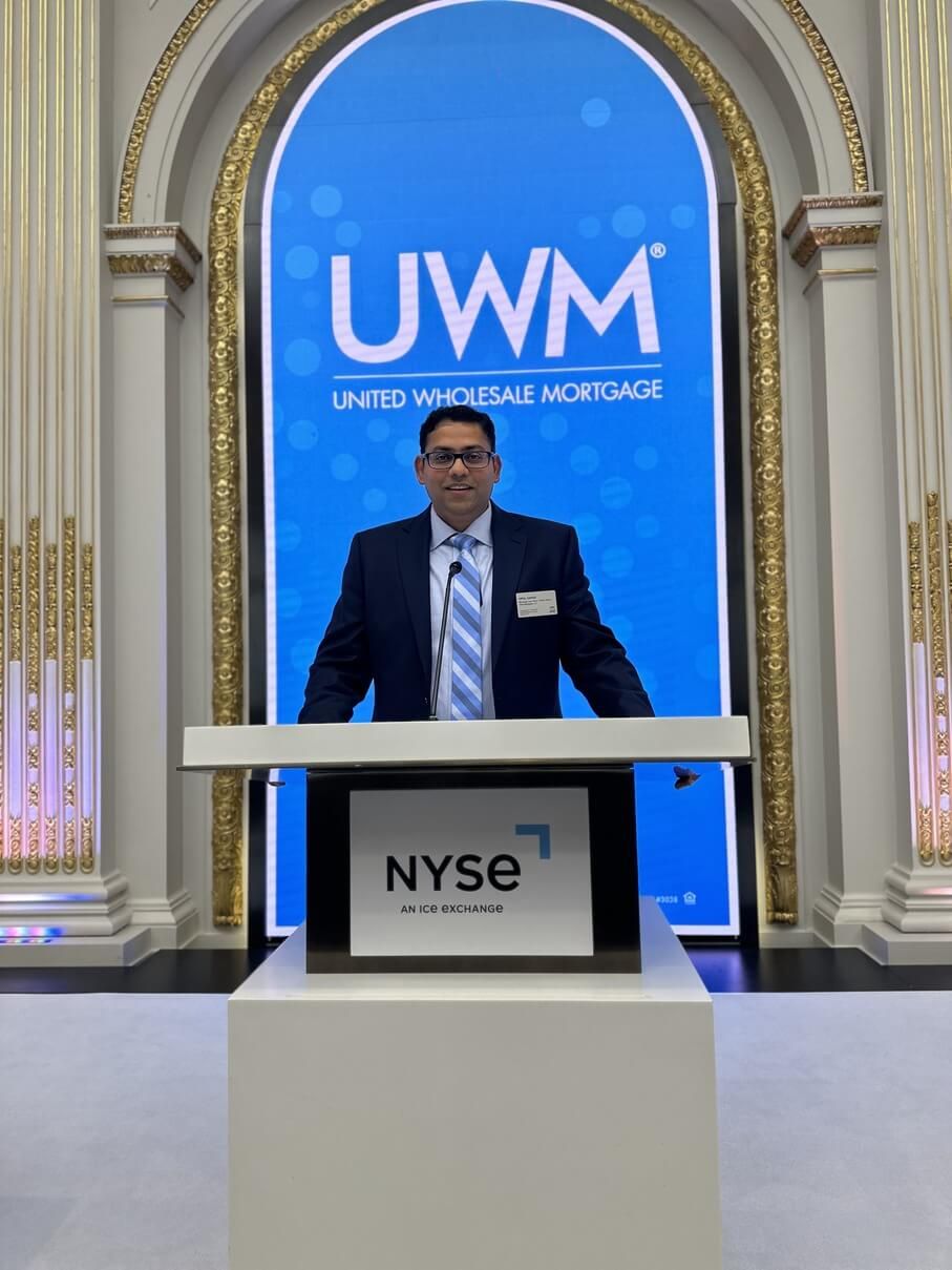 Man standing at NYSE podium in front of blue UWM logo backdrop