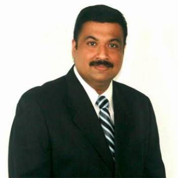 Man in a dark suit and striped tie posing against a white background