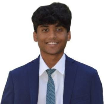 Smiling person in a blue suit and tie against a plain white background