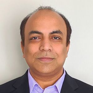 Headshot of a person in a dark blazer and light purple shirt against a plain white background
