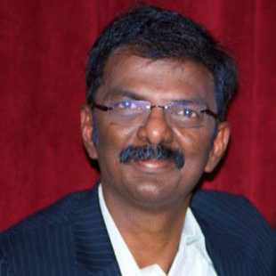 Portrait of a man in glasses and a dark suit against a red backdrop