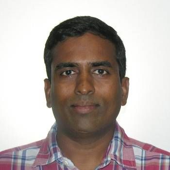 Portrait of a man wearing a pink plaid shirt against a plain white background