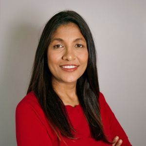 Portrait of a smiling woman in a red top against a neutral background