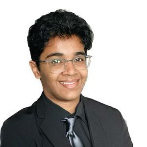 Portrait of a smiling person in a black suit, tie, and glasses on a white background