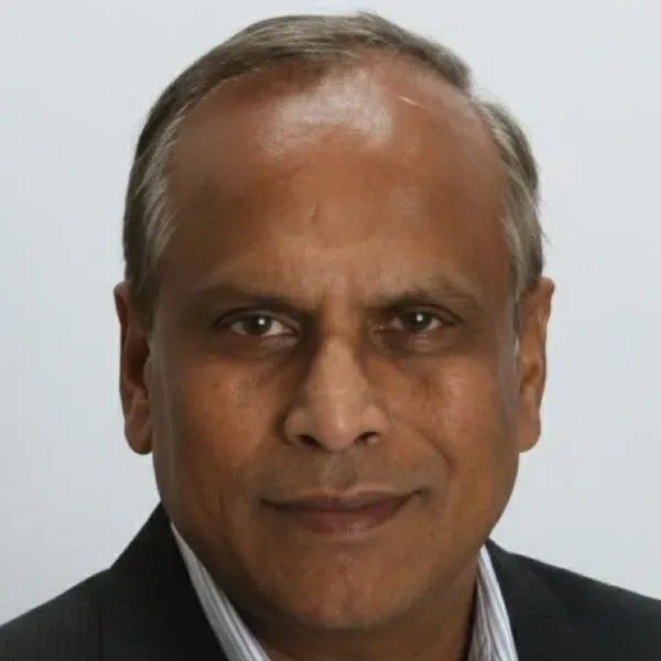 Studio headshot of a man in a dark suit against a light gray background
