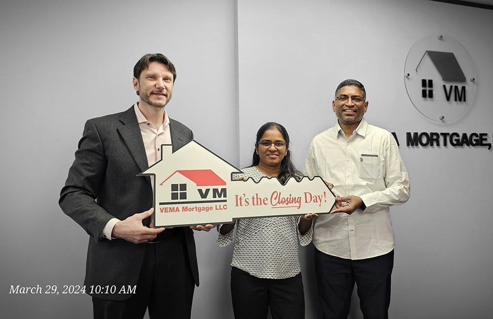 Three people hold a VM Mortgage sign at a celebratory event.
