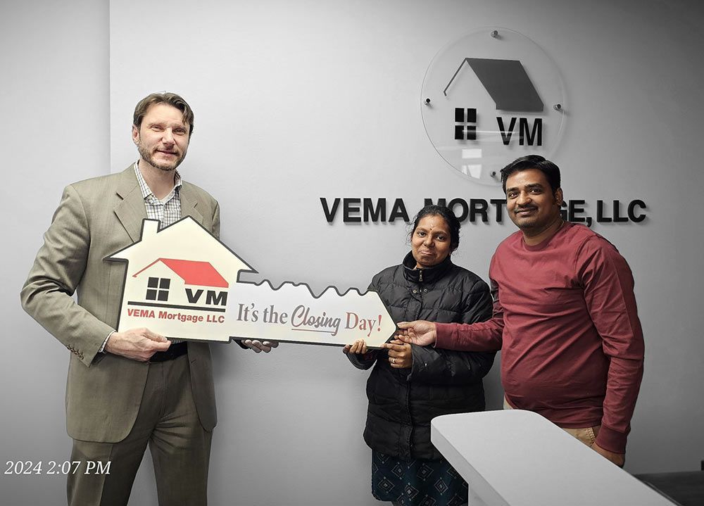 Three people holding a VEMA Mortgag e LLC sign and key-shaped award in an office lobby
