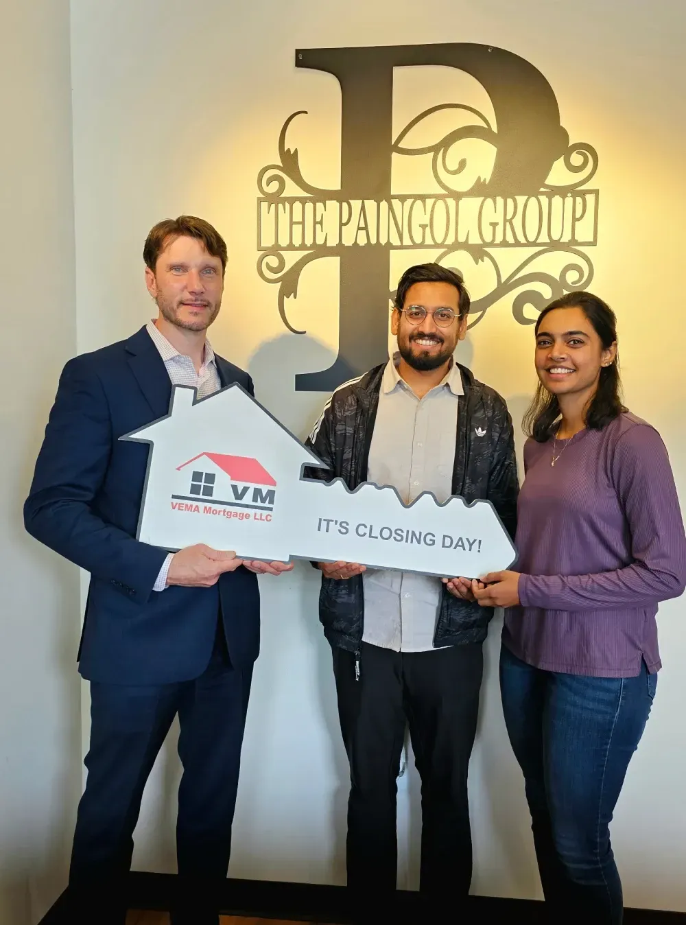 Three people hold a large check-style sign in front of a Finance Group wall logo.