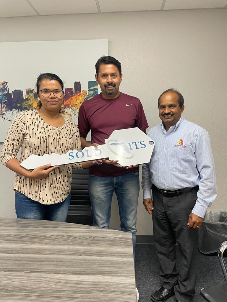 Three people holding a “SOLUTIONS” cutout in an office setting, smiling at the camera.