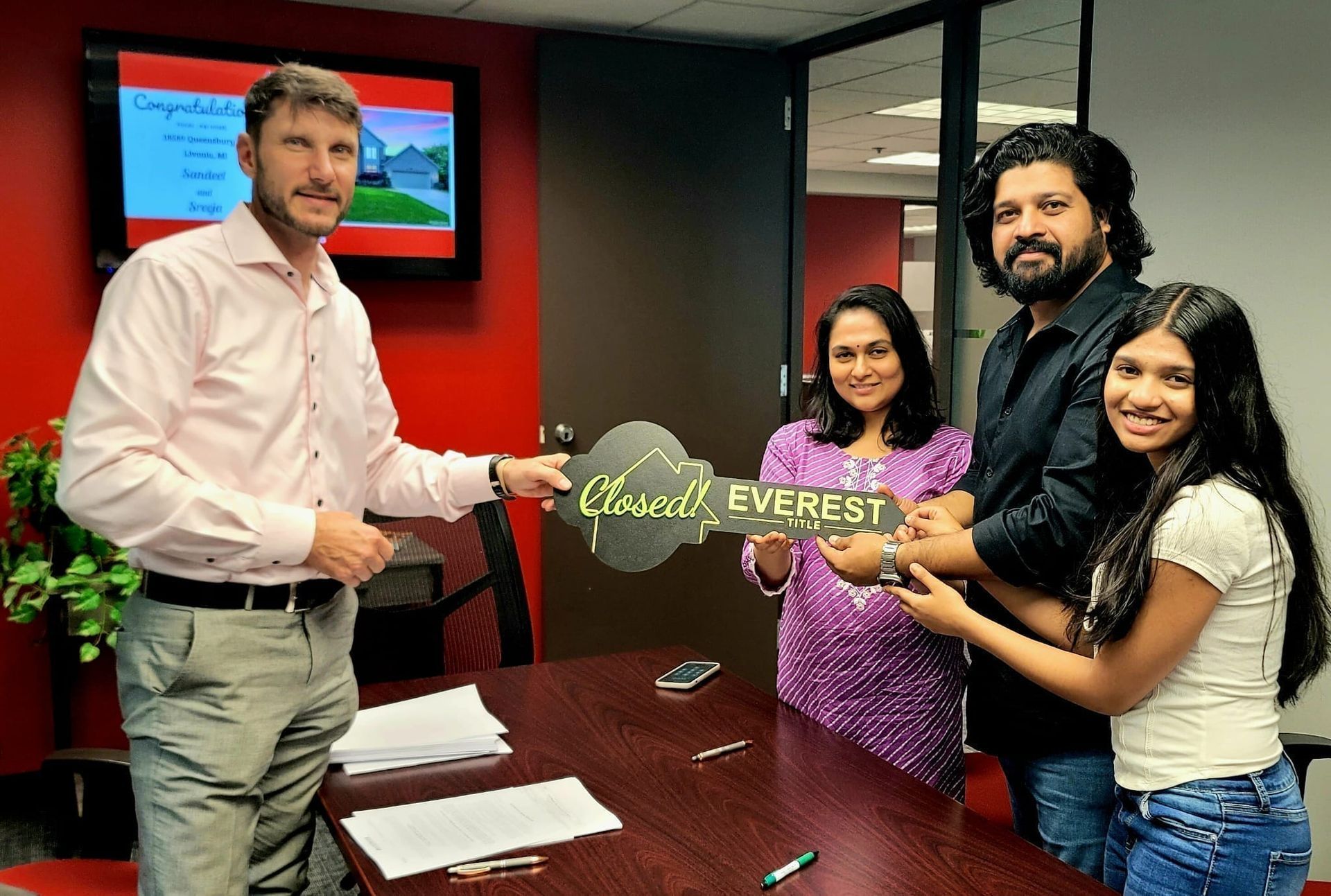 Four people in an office present a sign that says “Cloud Everest” by a conference table.
