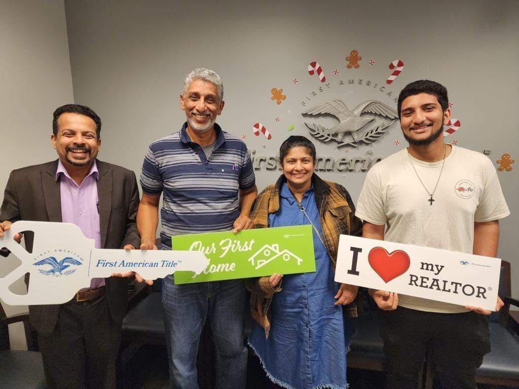Four people indoors holding signs, including one that says “I ♥ my REALTOR,” smiling at the camera.