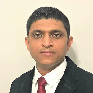 Formal headshot of a person in a black suit, white shirt, and red tie against a plain light background