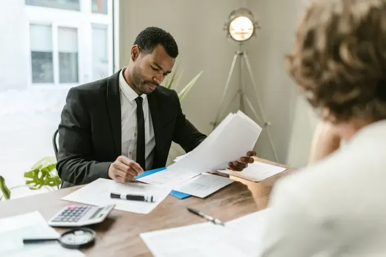 Two people reviewing documents at a desk in a bright office