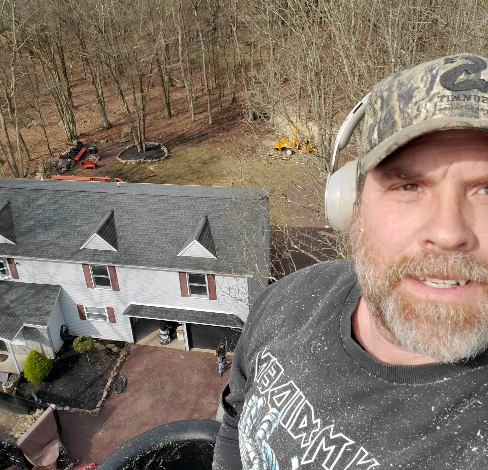 A man wearing headphones and a hat is standing in front of a house.