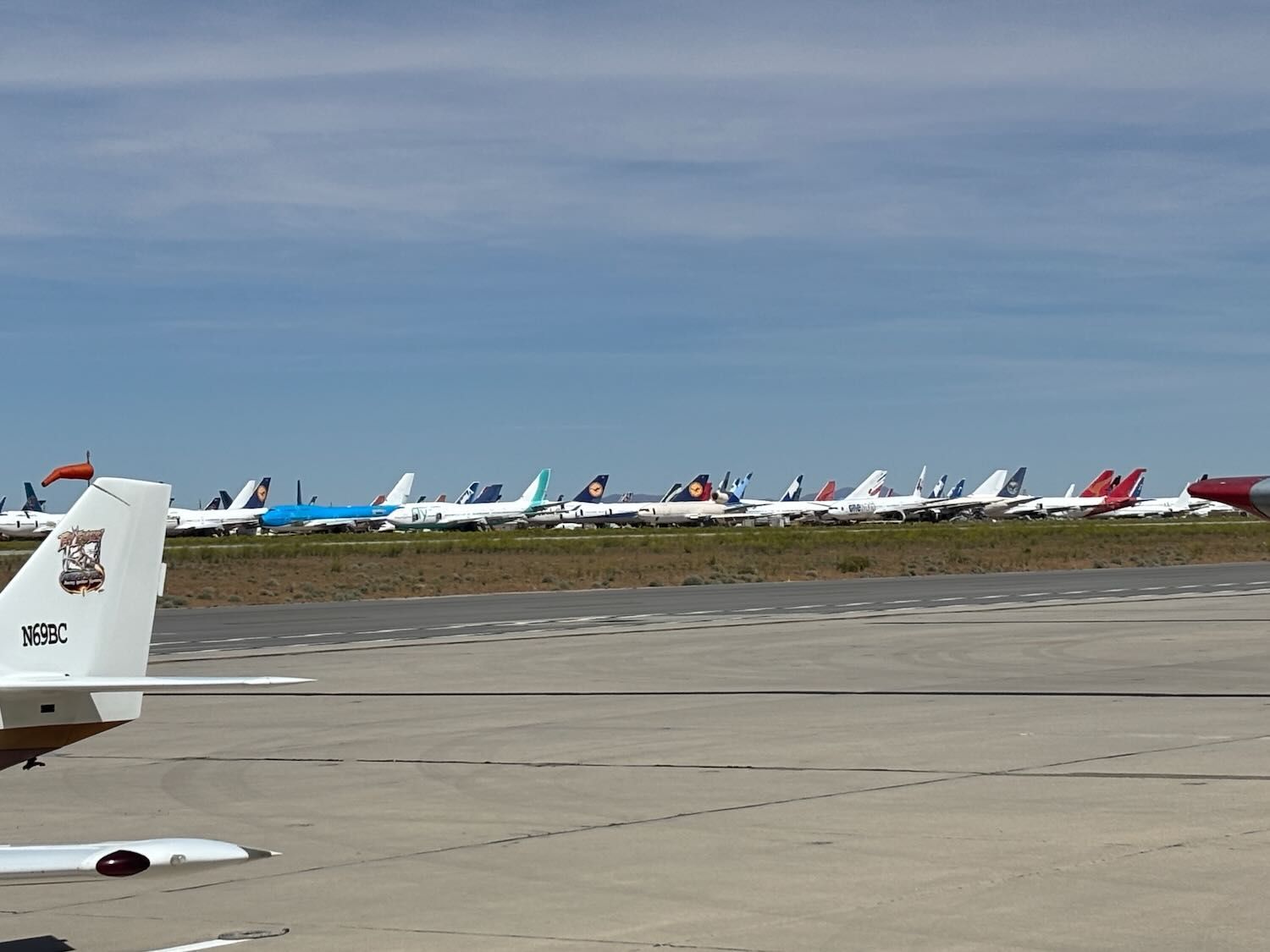 Airport tarmac with a row of parked airplanes under a cloudy sky