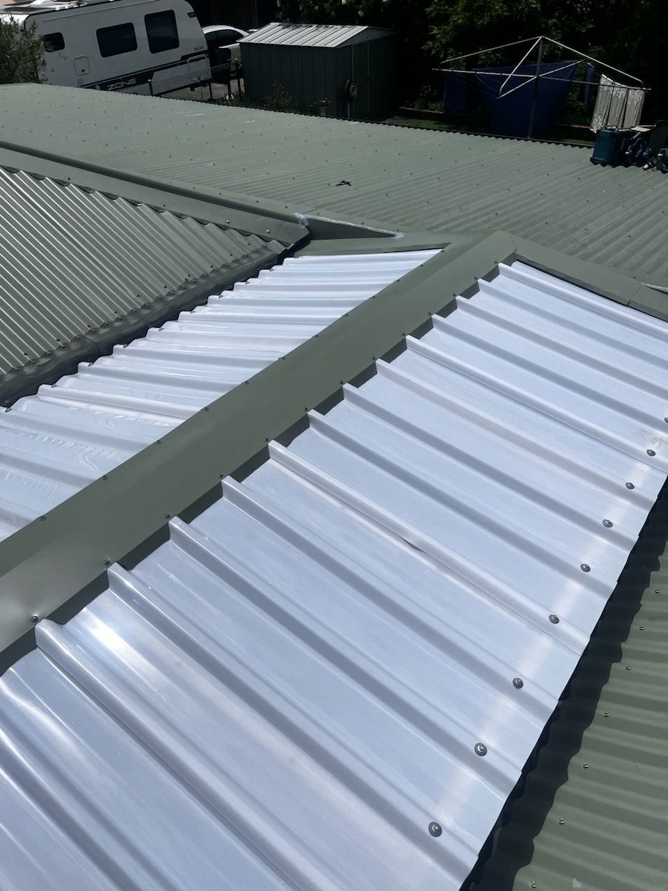A close up of a white metal roof with a green roof — Rooftech Roofing Services in Northern Rivers, NSW