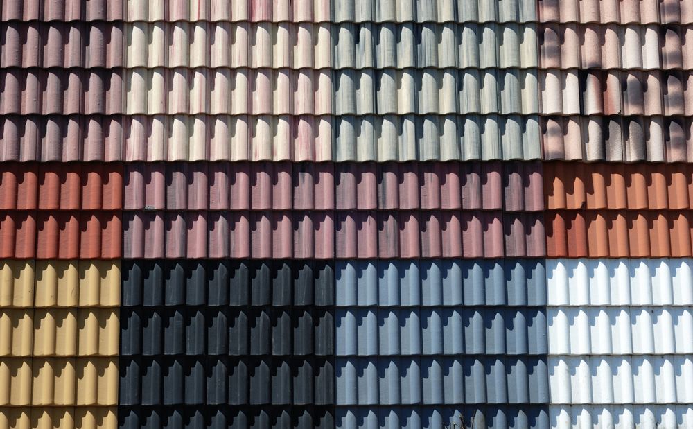 Roof tiles in a gradient of colors: yellow, black, brown, blue, and white.