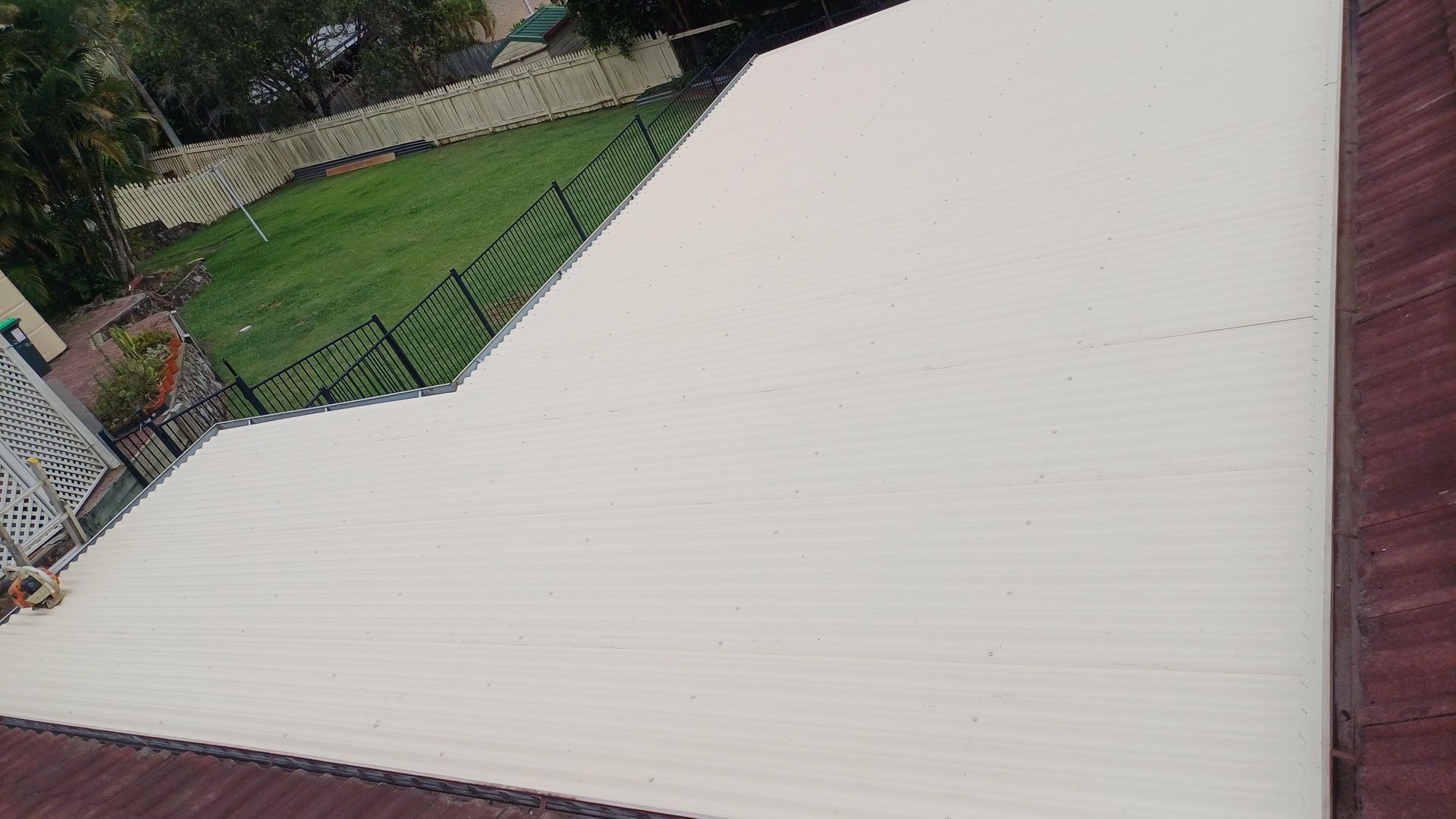 An Aerial View Of A White Roof With A Fence In The Background — Rooftech Roofing Services in Lismore, NSW