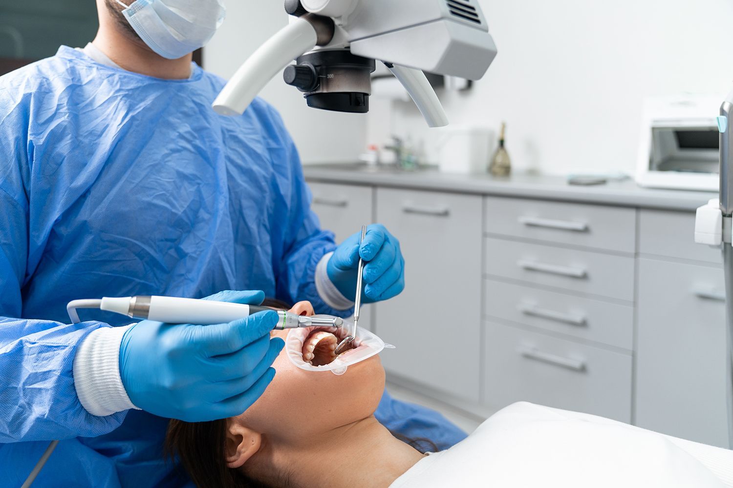 Endodontics specialist performing a dental procedure with microscope and precision instruments.