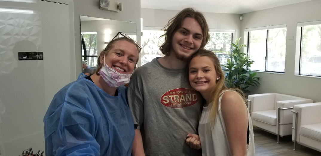 Family Dentistry team member smiling with two teen patients in the dental office