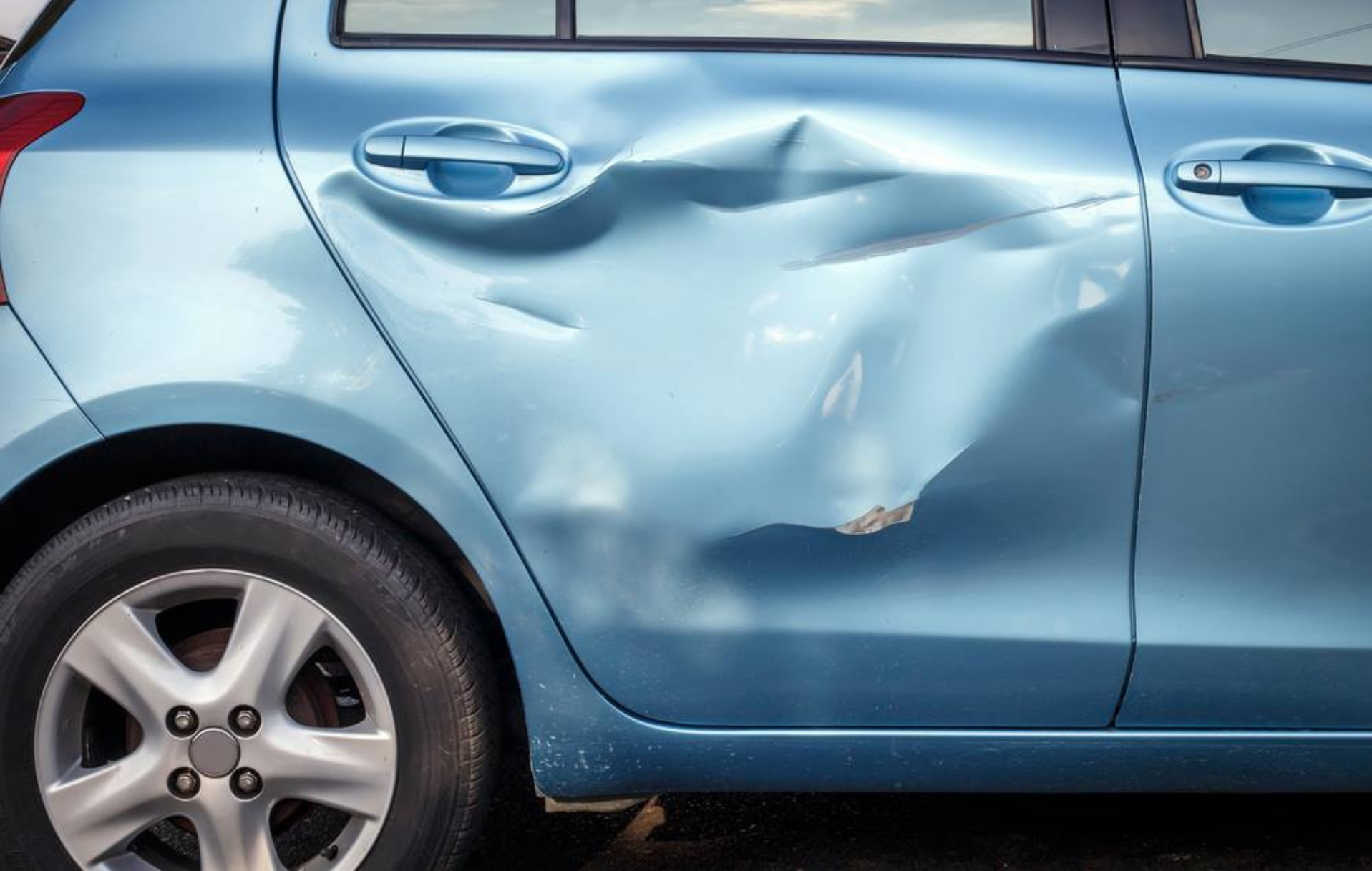 Blue car with a large dent on the rear passenger door
