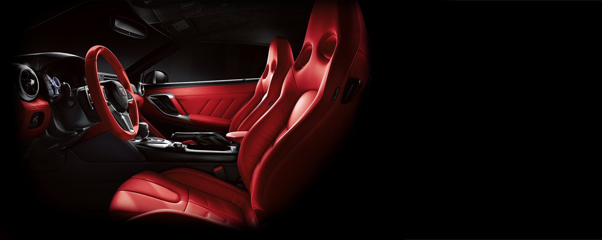 The interior of a car with red seats and a steering wheel.