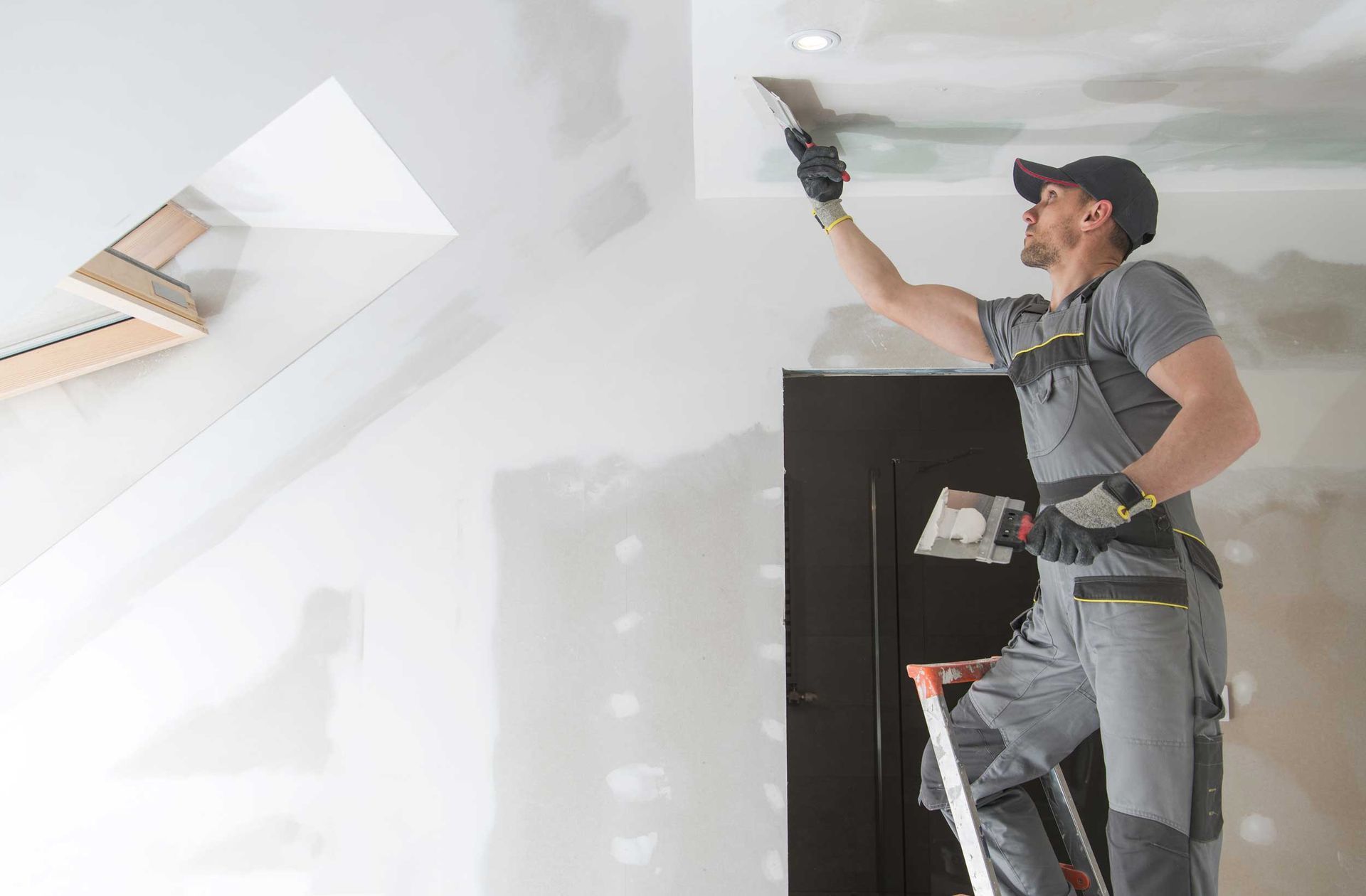 Worker on ladder using a power sander to smooth a white ceiling. Worker on ladder using a power sander to smooth a white ceiling.