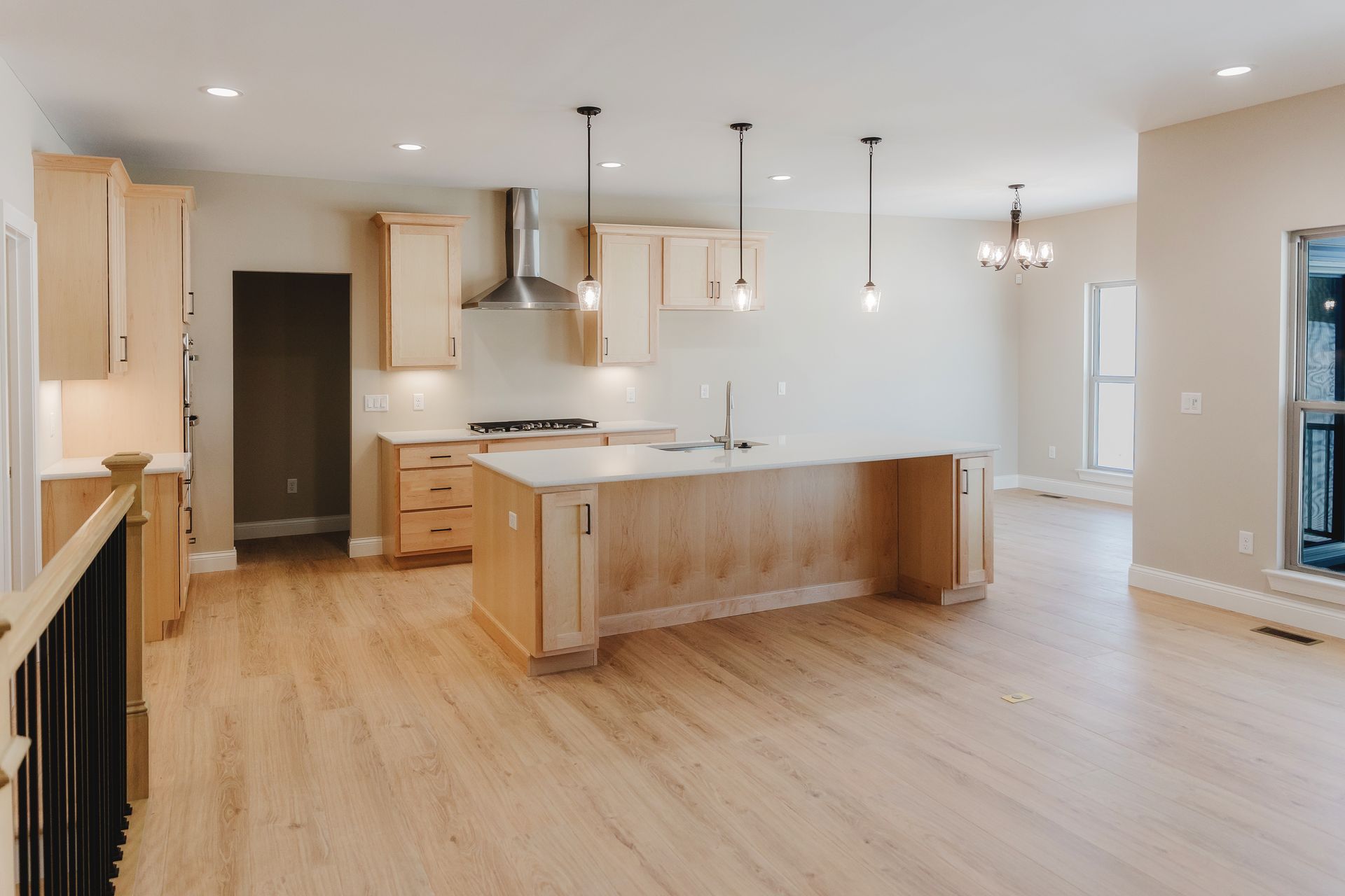 Modern kitchen of the Dean Martin model with light wood cabinets, island, and pendant lights.