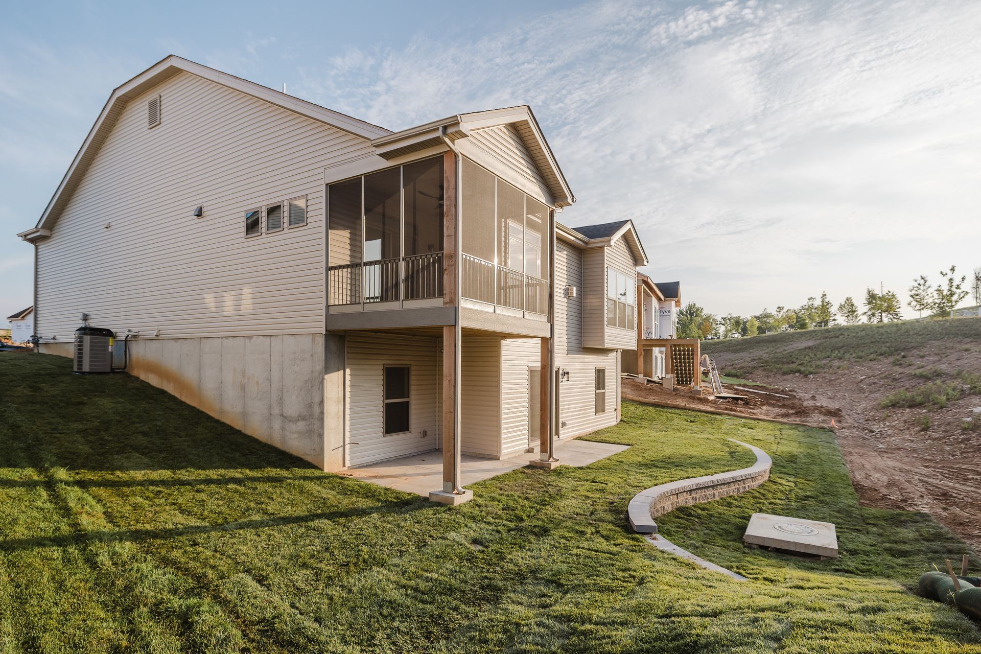 Side view of the Humphrey Bogart model with a screened porch and sloping green yard.