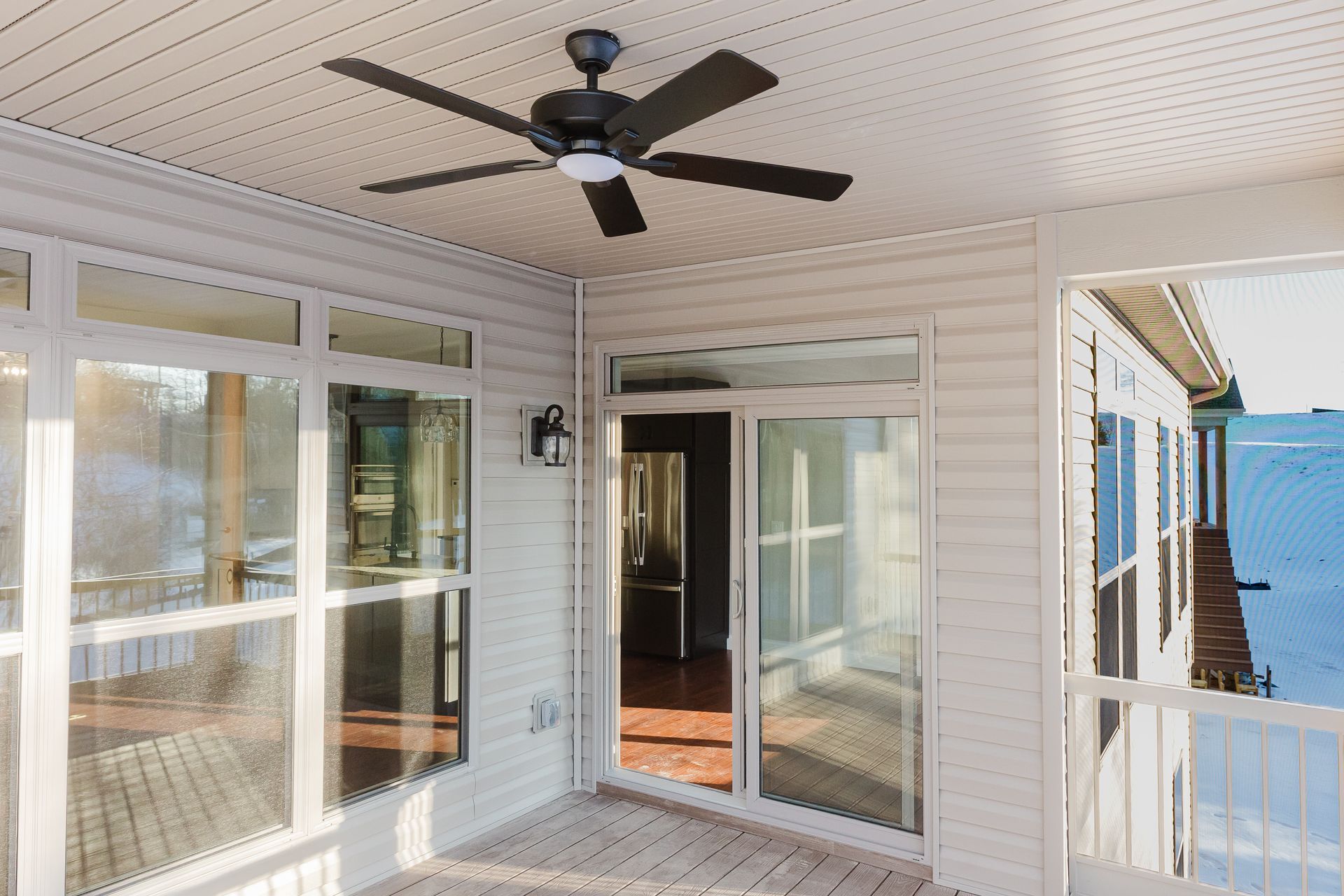 Screened porch of the Dean Martin model with ceiling fan, glass sliding door, and windows overlooking a deck.